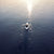 Man rowing origami canoe, MyCanoe Solo 2, on blue water towards the sunrise