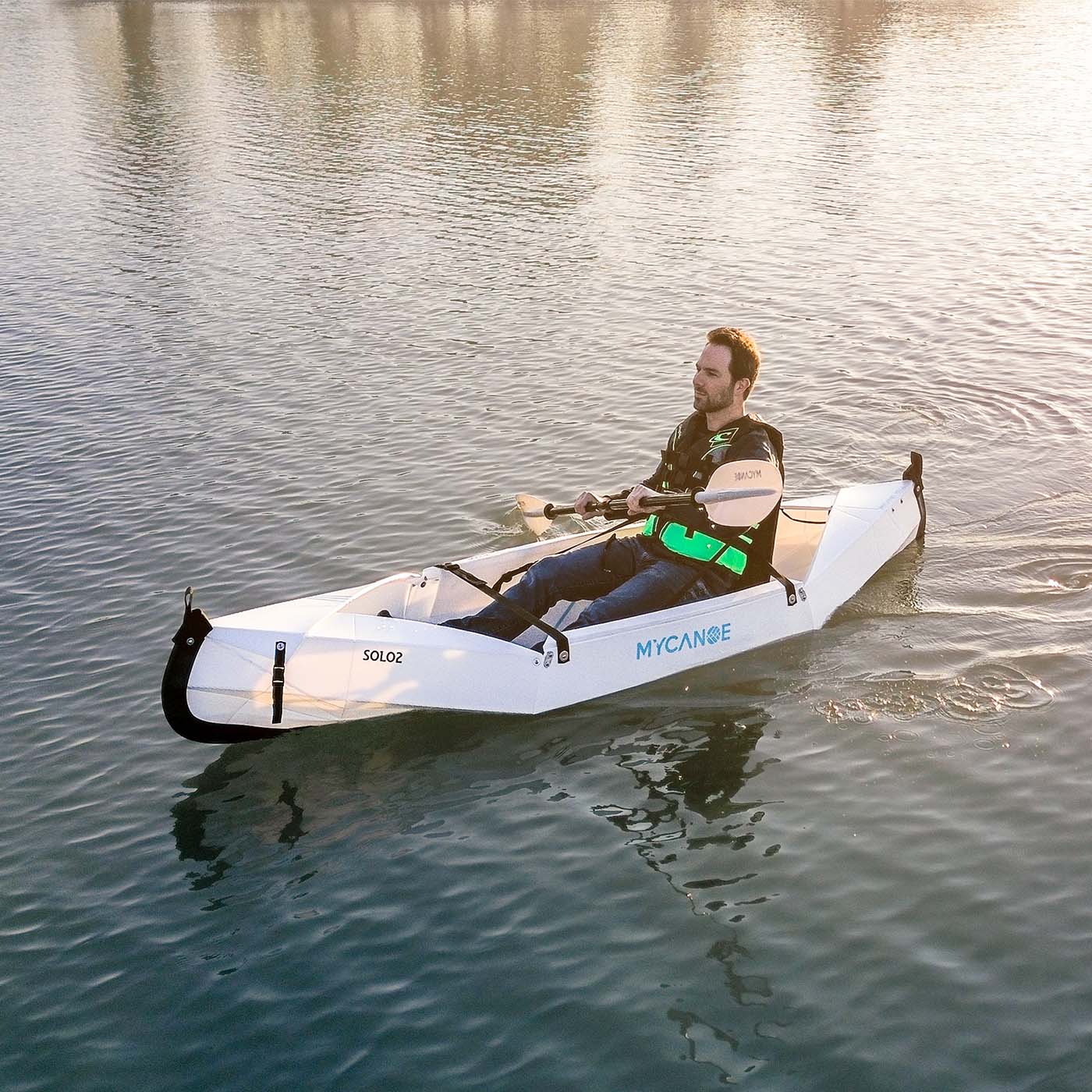 Man paddling in a folding canoe during sunset